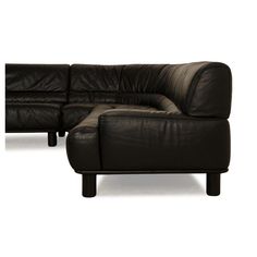 a black leather sectional sofa and ottoman in front of a white background with the foot rest down