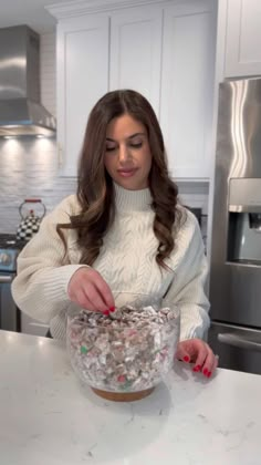 a woman standing in front of a counter with a bowl filled with candy and sprinkles