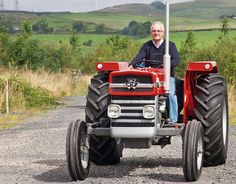 a man sitting on the front of a red tractor