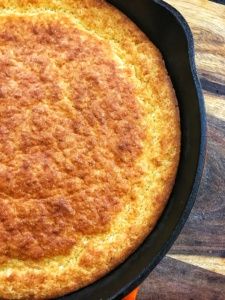 a skillet with some food in it on top of a wooden table next to an orange spatula