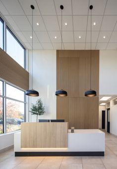 an office lobby with large windows and wood paneling on the wall, along with two desks