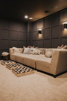 a living room with couches and rugs on the floor in front of dark paneled walls