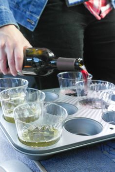 a person pouring wine into cups on a tray