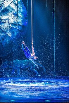 a man is suspended on a rope in the air with water splashing around him