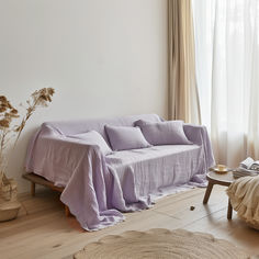 a living room with a couch covered in a purple blanket next to a coffee table