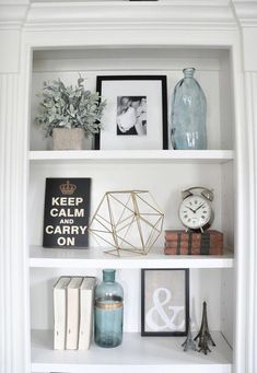 a white book shelf filled with books and vases on top of eachother