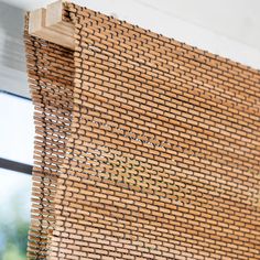 a close up of a window with a wooden frame and woven material on the outside