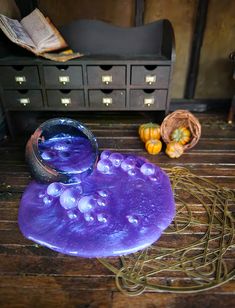 a purple object sitting on top of a wooden table next to a basket filled with pumpkins