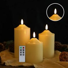 three lit candles with remote controls sitting on a table