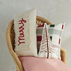 some pillows are sitting on a chair with a pink pillow and white wall in the background