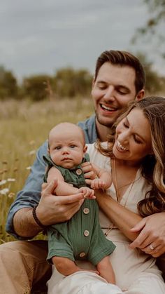 a man and woman holding a baby in a field