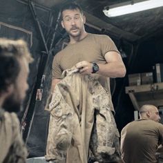 a man standing in front of a group of people holding onto some cloths and looking at the camera