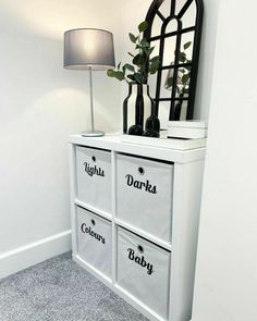 a white dresser with two drawers and a lamp