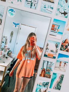 a woman taking a selfie in front of a mirror with pictures on the wall