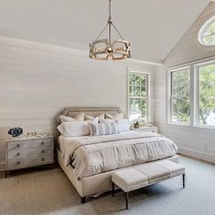 a bedroom with white walls and carpeted flooring, a large bed in the center