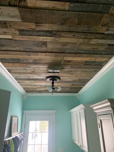 the ceiling in this kitchen is made out of wood planks and has a light fixture