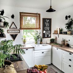 a kitchen filled with lots of counter top space next to a window covered in potted plants