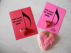 two valentine's day cards with heart shaped cookies and candy on the table next to them