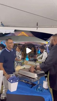 two men are serving themselves food at an outdoor event