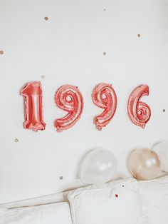 balloons spelling out the number nineteen nine on a bed