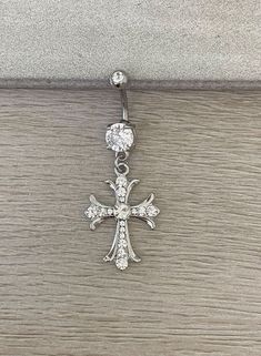 a silver cross is hanging on a wooden surface with a diamond bead around it