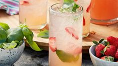 two glasses filled with drinks and strawberries on a table