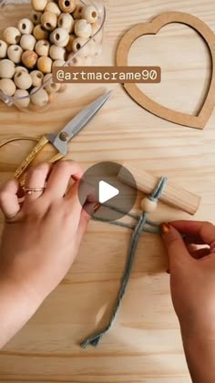 someone is making something out of wood and string with scissors on a wooden table next to other items