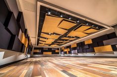 an empty room with wooden flooring and black and yellow panels on the ceiling,