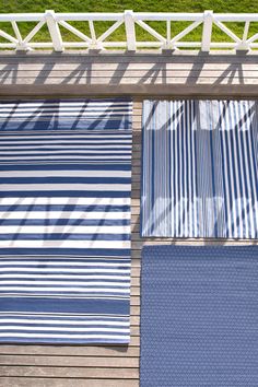 three blue and white striped towels sitting on top of a wooden deck