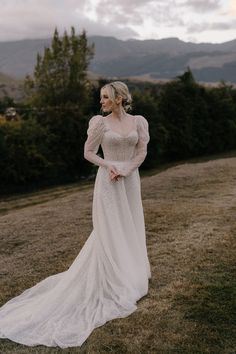 a woman in a white dress standing on top of a grass covered field