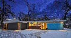 a house that is in the snow at night with lights on and trees around it