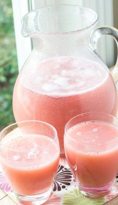 pitcher and two glasses filled with liquid on a table