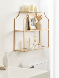 a bathroom shelf with candles, pictures and other items on it next to a toilet