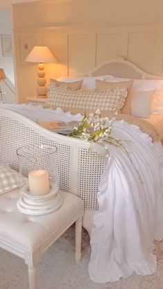 a white bed sitting in a bedroom next to a table with a candle on it