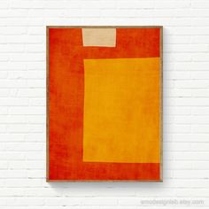 an orange and yellow painting hanging on a white brick wall