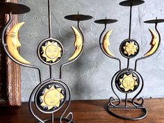 three metal sun and moon candle holders on a table