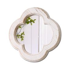 a white mirror with a plant in the middle and a reflection on it's side