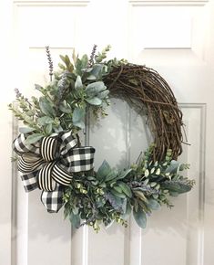 a wreath is hanging on the front door with greenery and ribbon tied around it