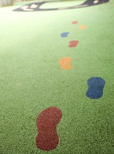 an outdoor playground with painted footprints on the ground and trees in the backgroud