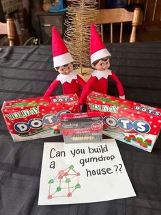 two elfs sitting on top of a table next to boxes of gummy's