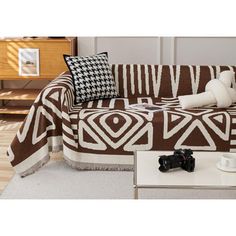 a brown and white couch sitting on top of a wooden floor next to a coffee table