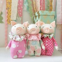 three stuffed pigs sitting next to each other on a table with pink and green decorations