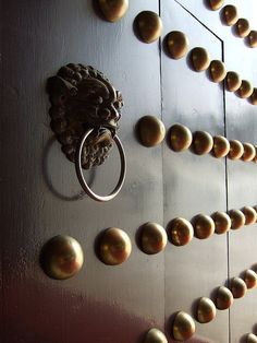 the door is decorated with gold balls and a lion's head knocker on it