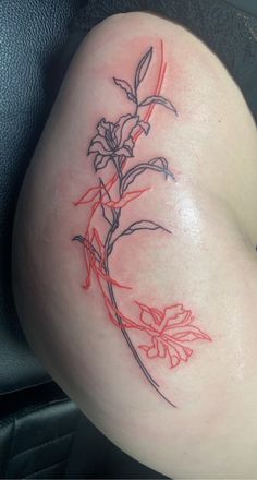 a tattoo on the back of a woman's thigh, with flowers and leaves