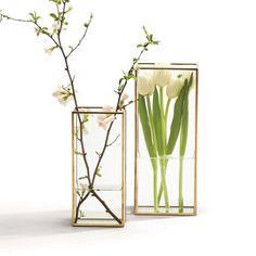 two vases with flowers in them on a white surface