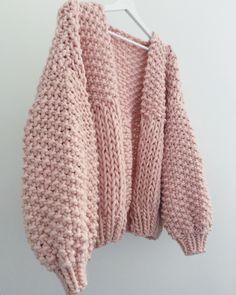 a pink sweater hanging on a white hanger