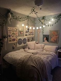 an unmade bed in a room with pictures on the wall and lights hanging from the ceiling