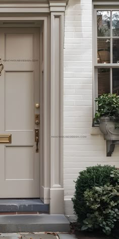 the front door to a white house with potted plants