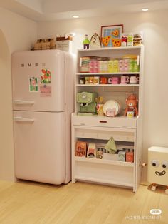 a white refrigerator freezer sitting inside of a kitchen next to a shelf filled with toys