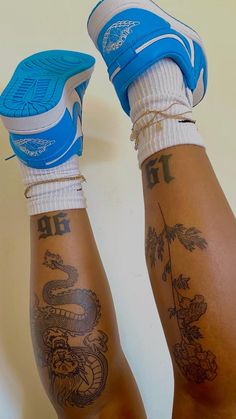 two legs with tattoos on them and one has a blue shoe in the other hand